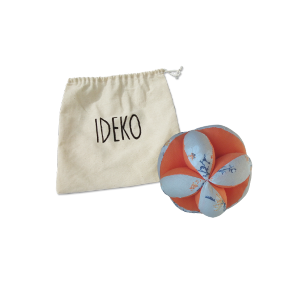 Une balle de préhension IDEKO en tissu coloré, douce au toucher, conçue pour stimuler le développement sensoriel et la coordination motrice des bébés et des tout-petits
